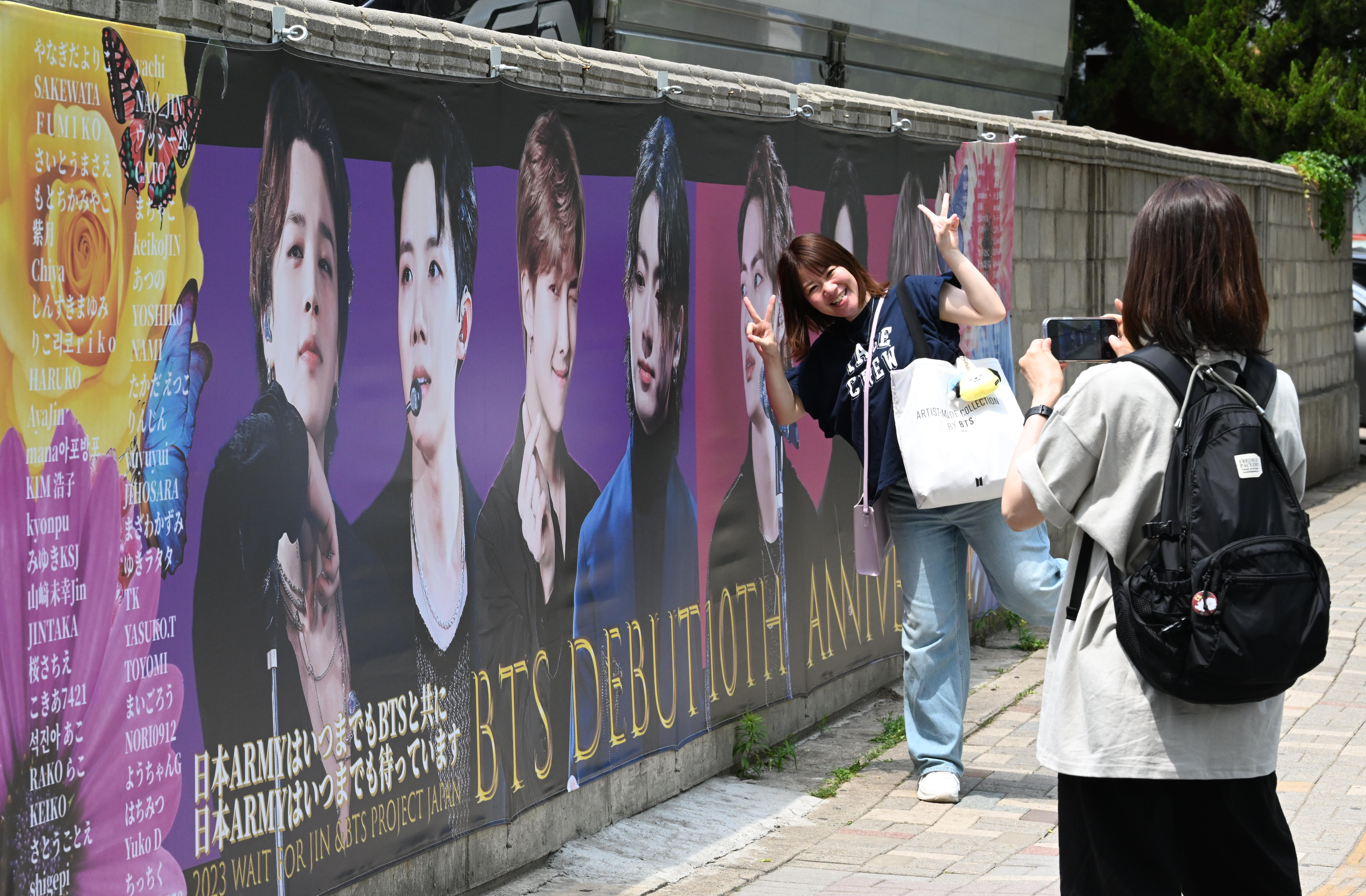 지난 12일 서울 용산구 하이브 사옥 인근에서 외국인 팬들이 방탄소년단(BTS) 데뷔 10주년 기념 그림 앞에서 사진을 찍고 있다. 도준석 기자
