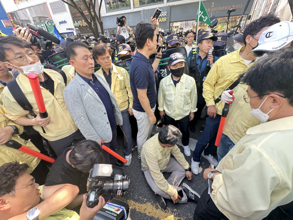 17일 오전 대구 중구 반월당역 인근에서 퀴어문화축제 측 무대차량 진입을 위해 교통 정리에 나선 경찰관들과 이를 막으려는 대구시 공무원들이 대치한 가운데 대구시 한 간부 공무원이 부상을 주장하며 바닥에 앉아 있다. 2023.6.17 연합뉴스