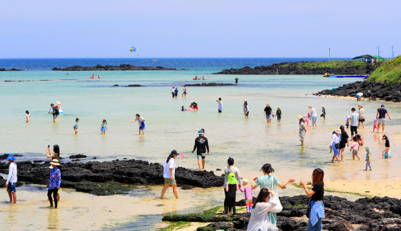 토요일인 17일 초여름 날씨 속 제주시 조천읍 함덕해수욕장에서 관광객과 나들이객들이 바닷물에 다리를 담그고 바닷바람을 쐬는 등 여름 정취를 즐기고 있다. 2023.6.17 연합뉴스