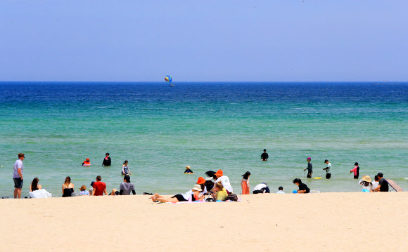토요일인 17일 초여름 날씨 속 제주시 조천읍 함덕해수욕장에서 관광객과 나들이객들이 바닷물에 다리를 담그고 바닷바람을 쐬는 등 여름 정취를 즐기고 있다. 2023.6.17 연합뉴스