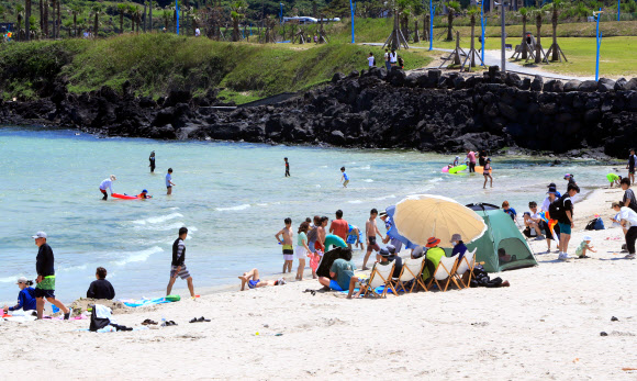 토요일인 17일 초여름 날씨 속 제주시 조천읍 함덕해수욕장에서 관광객과 나들이객들이 바다에 들어가 물놀이하거나 백사장에 앉아 바닷바람을 쐬며 여름 정취를 즐기고 있다. 2023.6.17 연합뉴스