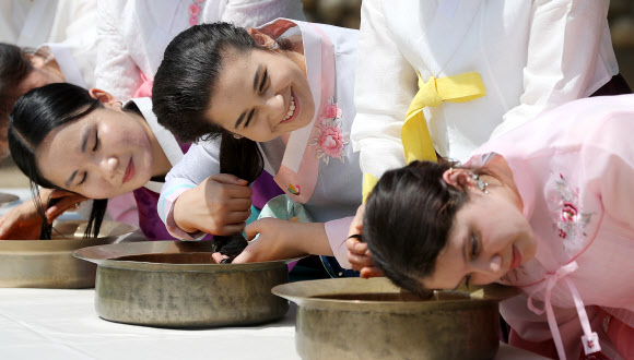 음력 5월 5일 전통 명절 단오를 이틀 앞둔 20일 오전 경북 경산시 영남대학교 민속촌에서 외국인 유학생들이 창포물에 머리감기 체험을 하고 있다. 예부터 단오에 창포를 삶은 물로 머리를 감으면 창포 특유의 향기로 나쁜 귀신을 쫓고, 머리에 윤기가 난다고 믿었다. 2023.6.20 연합뉴스
