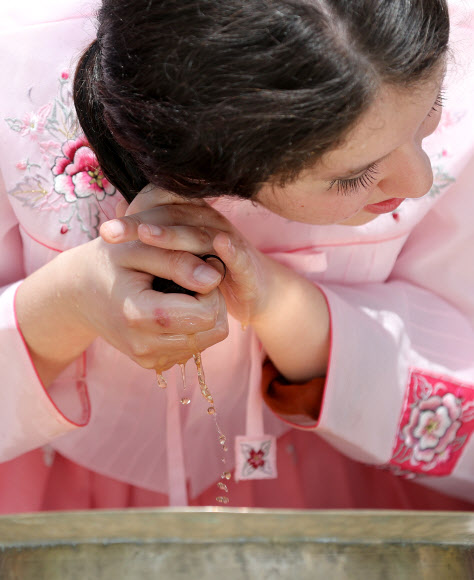 음력 5월 5일 전통 명절 단오를 이틀 앞둔 20일 오전 경북 경산시 영남대학교 민속촌에서 외국인 유학생들이 창포물에 머리감기 체험을 하고 있다. 예부터 단오에 창포를 삶은 물로 머리를 감으면 창포 특유의 향기로 나쁜 귀신을 쫓고, 머리에 윤기가 난다고 믿었다. 2023.6.20 연합뉴스