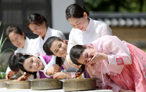 음력 5월 5일 전통 명절 단오를 이틀 앞둔 20일 오전 경북 경산시 영남대학교 민속촌에서 외국인 유학생들이 창포물에 머리감기 체험을 하고 있다. 예부터 단오에 창포를 삶은 물로 머리를 감으면 창포 특유의 향기로 나쁜 귀신을 쫓고, 머리에 윤기가 난다고 믿었다. 2023.6.20 연합뉴스