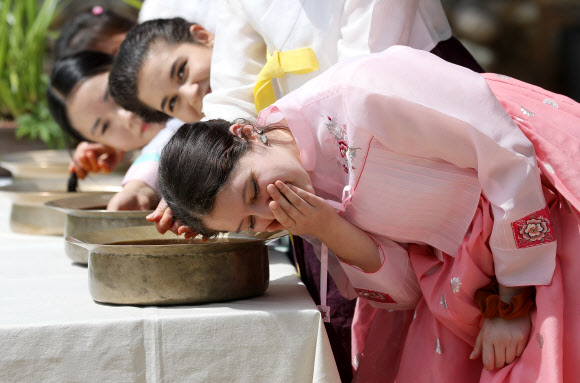 음력 5월 5일 전통 명절 단오를 이틀 앞둔 20일 오전 경북 경산시 영남대학교 민속촌에서 외국인 유학생들이 창포물에 머리감기 체험을 하고 있다. 예부터 단오에 창포를 삶은 물로 머리를 감으면 창포 특유의 향기로 나쁜 귀신을 쫓고, 머리에 윤기가 난다고 믿었다. 2023.6.20 연합뉴스