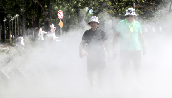 대구에 폭염주의보가 발효 중인 28일 오후 대구 중구 대봉동 인도에 설치된 쿨링포그 사이로 시민들이 더위를 식히며 걸어가고 있다. 2023.6.28 연합뉴스