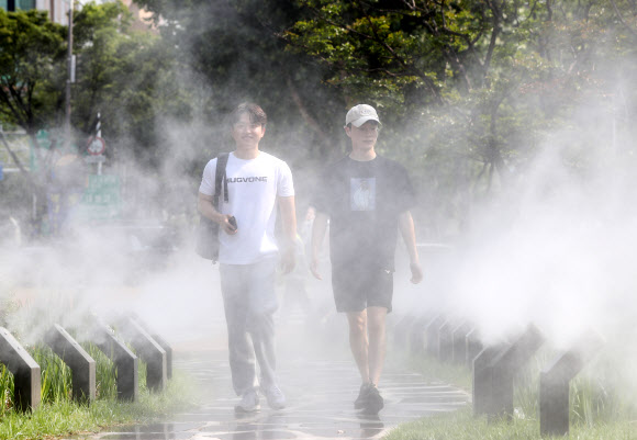 대구에 폭염주의보가 발효 중인 28일 오후 대구 중구 대봉동 인도에 설치된 쿨링포그 사이로 시민들이 더위를 식히며 걸어가고 있다. 2023.6.28 연합뉴스