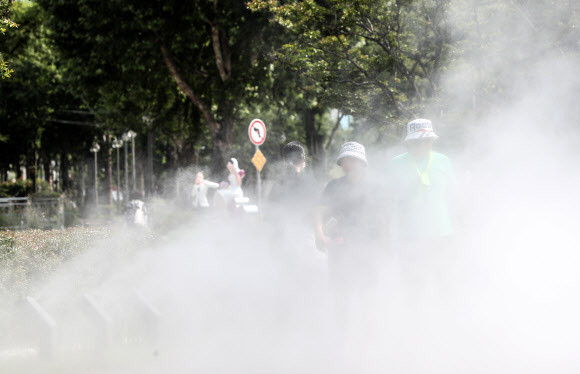 대구에 폭염주의보가 발효 중인 28일 오후 대구 중구 대봉동 인도에 설치된 쿨링포그 사이로 시민들이 더위를 식히며 걸어가고 있다. 2023.6.28 연합뉴스