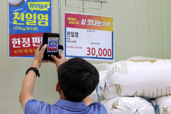 정부가 천일염 비축분 공급을 시작한 29일 오전 서울 시내 한 대형마트에서 한 시민이 정부 비축 천일염 판매 안내문을 촬영하고 있다. 해양수산부는 천일염 가격 안정을 위해 이날부터 다음달 11일까지 정부 비축 천일염을 전국 마트와 전통시장에 최대 400t 공급한다. 2023.6.29 연합뉴스