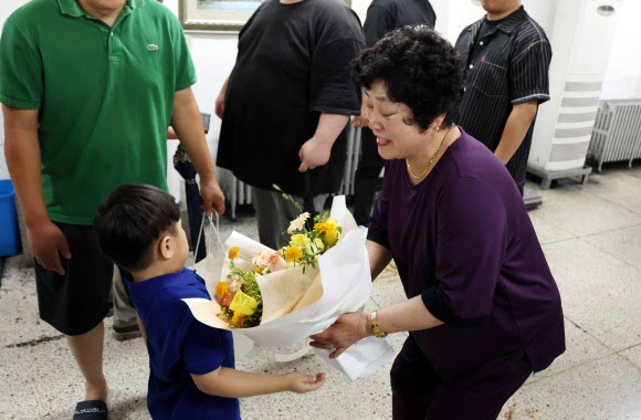 전남 화순탄광이 폐광한 30일 오전 전남 화순군 동면 대한석탄공사 화순광업소에서 한 여성 근로자가 손자에게 꽃다발을 받고 있다. 2023.6.30 연합뉴스