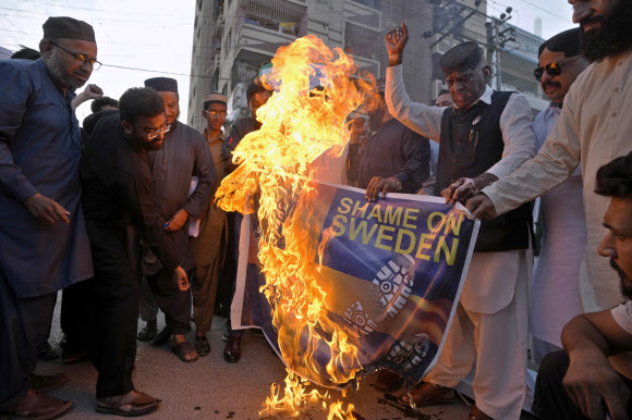 2일(현지시간) 파키스탄 카라치에서 이슬람포럼연합 활동가들이 최근 스웨덴에서 벌어진 이슬람 경전 쿠란 소각 시위에 항의하며 스웨덴 국기를 불태우고 있다. 2023.7.2 AP 연합뉴스