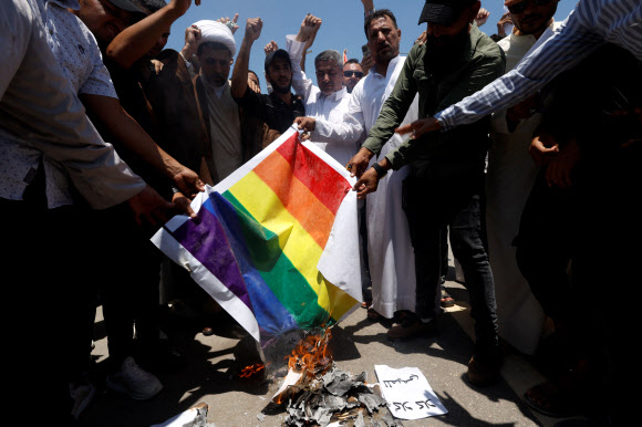 30일(현지시간) 이라크 바그다드의 스웨덴 대사관 앞에서 시아파 무슬림 지도자 무크타다 알사드르의 지지자들이 최근 스웨덴에서 벌어진 이슬람 경전 쿠란 소각 시위에 항의하며 성소수자(LGBTQ+) 무지개 깃발을 밟고 있다. 2023.6.30 로이터 연합뉴스