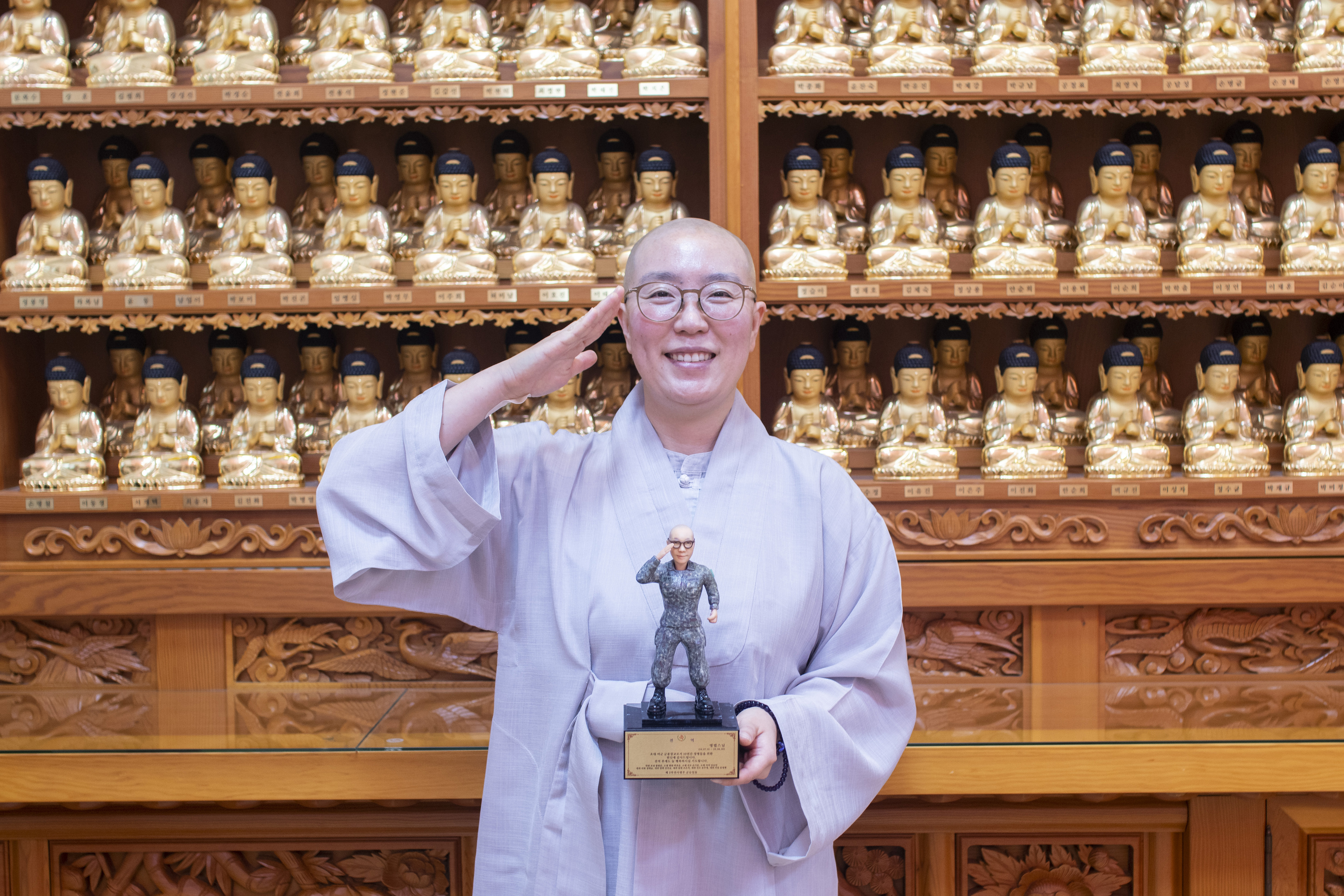 국내 첫 여성 군종장교 생활을 마치고 전역한 명법 스님이 4일 부산 금련사에서 부대원들이 만들어준 피규어를 들고 거수경례를 하고 있다.