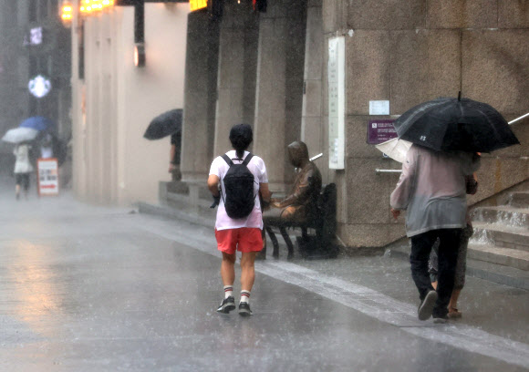 9일 오전 서울 종로구 광화문광장에 갑자기 소나기가 내리자 한 시민이 비를 맞으며 걸어가고 있다. 2023.7.9 연합뉴스