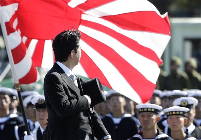 일본 자위대의 깃발로 사용되고 있는 ‘욱일기’를 향해 아베 신조 총리가 예를 갖추는 모습. 욱일기는 일본 제국주의 상징이다. AP 연합뉴스