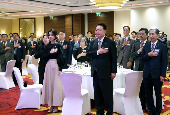 폴란드를 공식 방문한 윤석열 대통령과 김건희 여사가 12일(현지시간) 바르샤바 한 호텔에서 열린 동포간담회에서 국기에 경례하고 있다. 2023.7.13 연합뉴스