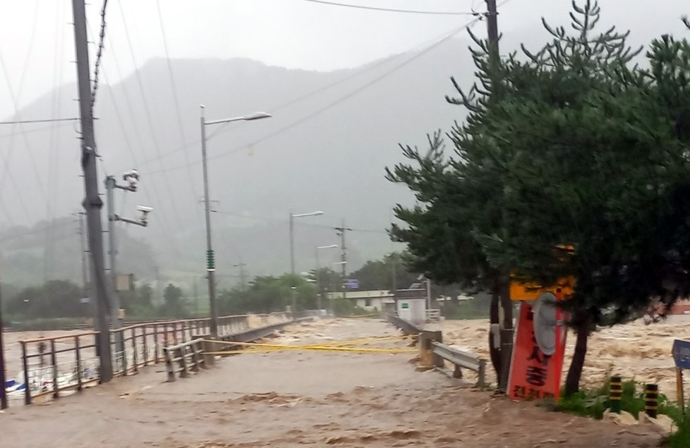 15일 오전 충북 괴산군 칠성면에 있는 괴산댐이 월류 중인 가운데 댐 아래에 있는 수전교도 물에 잠겨 통행이 통제되고 있다.  연합뉴스