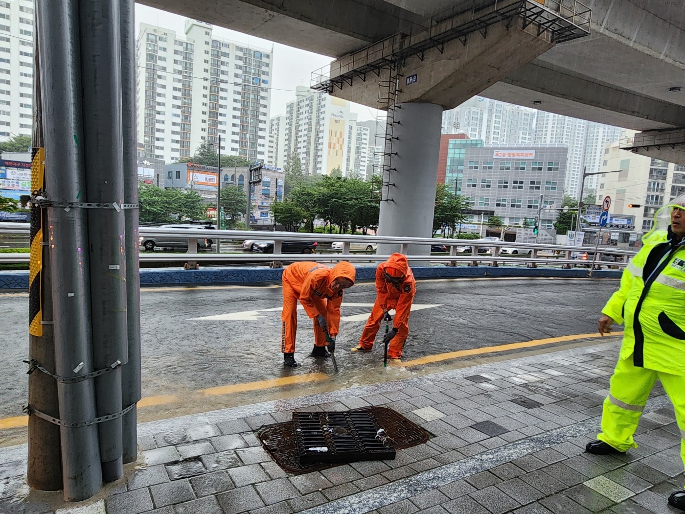 지난 16일 부산 해운대구 우동에서 폭우로 하수구가 역류해 소방 대원이 안전 조치를 하고 있다. 부산소방재난본부 제공