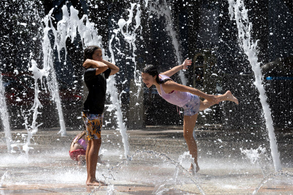 미국 텍사스주 휴스턴에 있는 디스커버리 그린 공원을 찾은 올리비아(10)와 에벌린 블랙(12) 자매가 게이트 웨이 분수에서 춤을 추며 놀고 있다. 휴스턴 로이터 연합뉴스