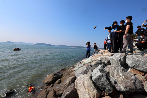 19일 오후 인천시 중구 덕교동 잠진도 제방에서 해경이 바다에 아내를 빠트리고 돌 던져 살해한 혐의를 받는 30대 남편 A씨에 대해 현장 검증에서 A씨가 바다에 빠진 아내에게 돌을 던지는 모습을 재현하고 있다. 2023.7.19 연합뉴스