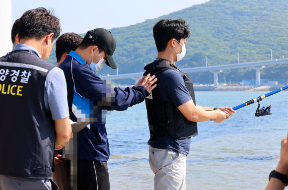 19일 오후 인천시 중구 덕교동 잠진도 제방에서 해경이 바다에 아내를 빠트리고 돌 던져 살해한 혐의를 받는 30대 남편 A씨에 대해 현장 검증에서 A씨가 낚시하는 아내를 바다로 미는 장면을 재현하고 있다. 2023.7.19 연합뉴스