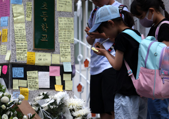20일 오전 서초구 한 초등학교 앞에 등굣길 학생들이 추모 메시지를 적고 있다.    교육계에 따르면 이 학교 담임 교사 A씨가 학교 안에서 극단적 선택을 해 숨지는 일이 발생했다. 2023.7.20 연합뉴스
