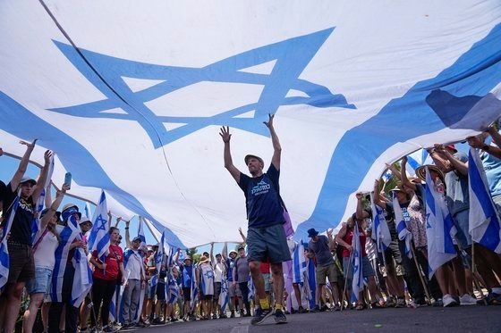 베냐민 네타냐후 총리가 주도하는 이스라엘 정부가 ‘사법장악안’을 추진하는 데 맞서 시위에 나선 시민들이 이스라엘 국기를 펼쳐 보이고 있다. AP 연합뉴스