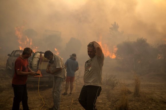 그리스 에게해의 로도스섬에 있는 겐나디 마을 주민들이 여드레째 산불이 이어진 25일(현지시간) 산불을 끄려고 안간힘을 쓰다 망연자실하고 있다. 에비아섬에서는 소방 비행기가 추락해 2명이 숨지기도 했다. 로도스섬 AP 연합뉴스