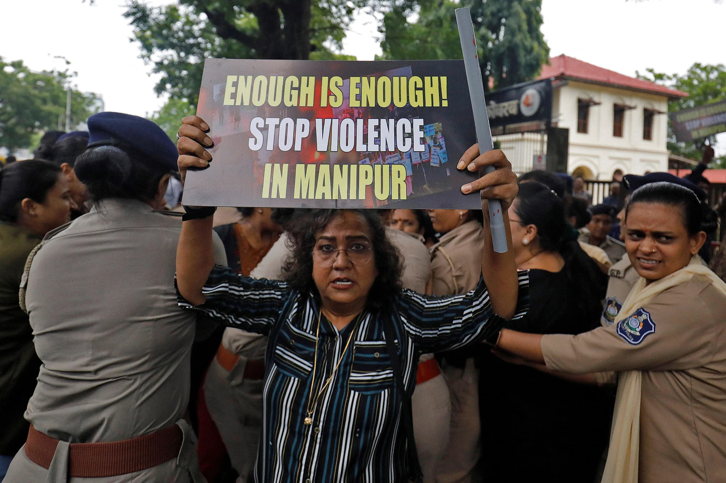 인도 북동부 마니푸르주에서 일어난 모녀 알몸 행진 및 집단 성폭행 사건에 분노한 여성이 23일(현지시간) 아메다바드에서 이 사건에 항의하기 위해 열린 집회 참가자들을 경관들이 연행하자 카메라를 향해 플래카드를 들어 보이고 있다. 로이터 자료사진