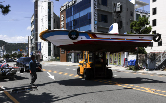 제6호 태풍 ‘카눈’이 한반도를 향해 북상 중인 7일 부산 해운대구 송정어촌계 어민들이 중장비를 이용해 어선을 옮기고 있다. 2023.8.7 연합뉴스
