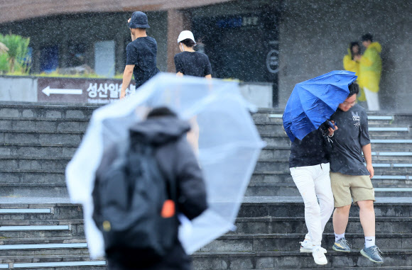 제6호 태풍 카눈이 한반도를 향해 접근 중인 9일 오후 제주 서귀포시 성산일출봉을 찾은 관광객들이 강한 비바람을 맞고 있다. 2023.8.9 연합뉴스