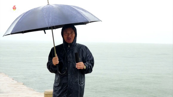 북한 조선중앙TV는 10일, 현재 경상남도 통영시 부근 지역에 상륙한 태풍6호(카눈)가 북한에 점차 영향을 주기 시작했다고 보도했다. 고성 앞바다에 나간 북한 기자가 우산을 쓰고 태풍 ‘카눈’ 소식을 전하고 있다. 2023.8.10. 조선중앙TV 화면·연합뉴스