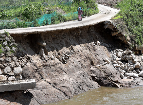 11일 대구 군위군 부계면 대율리 한 하천 인근 도로가 태풍 ‘카눈’의 영향으로 유실돼 위험하지만, 별다른 통제와 조치 없이 주민이 통행하고 있다. 2023.8.11 연합뉴스