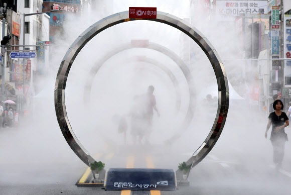 11일 오후 대전시 중구 은행동 일대에서 열리는 대전 0시 축제장을 찾은 방문객이 쿨링포그를 지나가며 더위를 식히고 있다. 2023.8.11 연합뉴스