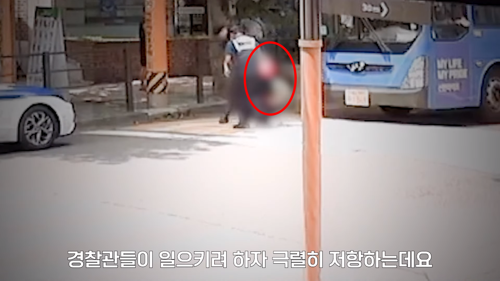 지난달 31일 서울 용산구 도로에서 신호 대기 중이던 버스 앞에서 한 여성이 “문을 열어달라”며 난동을 부렸다. 이 여성은 신호가 파란불로 바뀌었음에도 버스 앞을 가로막고 항의했다. 경찰이 여성을 일으키는 장면. 서울경찰 유튜브