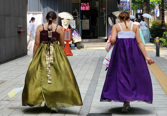 지난 19일 오후 무더위에 지친 외국인 관광객들이 저고리를 벗고 광화문 거리를 걸어가고 있다. 2023.8.20 연합뉴스