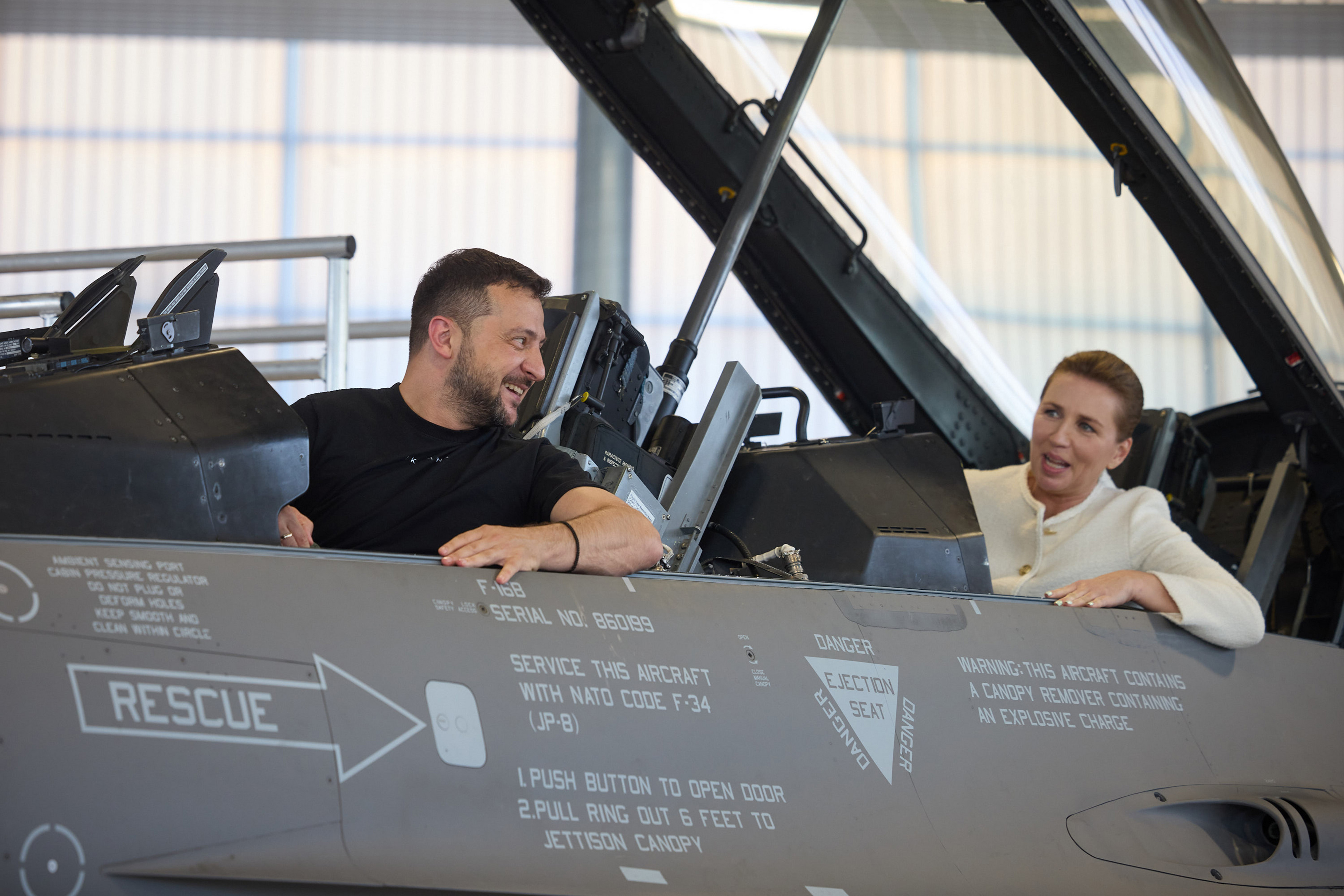 20일(현지시간) 깜짝 순방에 나선 볼로디미르 젤렌스키 우크라이나 대통령이 덴마크 보옌스에 있는 스크리드스트럽 공군기지 격납고에서 메테 프레데릭센(뒤) 덴마크 총리와 F-16 전투기에 앉아 있다. 2023.8.20 AFP 연합뉴스