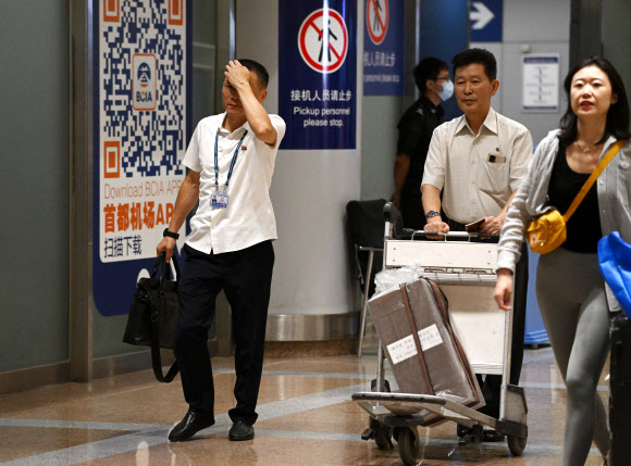 북한인으로 추정되는 두 남성이 22일 중국 베이징 서우두 공항 입국장을 빠져나오고 있다. 두  남성은 3년 7개월 만에 재개된 평양~베이징 항공 노선을 이용한 고려항공 여객기 JS 151편을 이용한 것으로 보인다. 베이징 AFP 연합뉴스