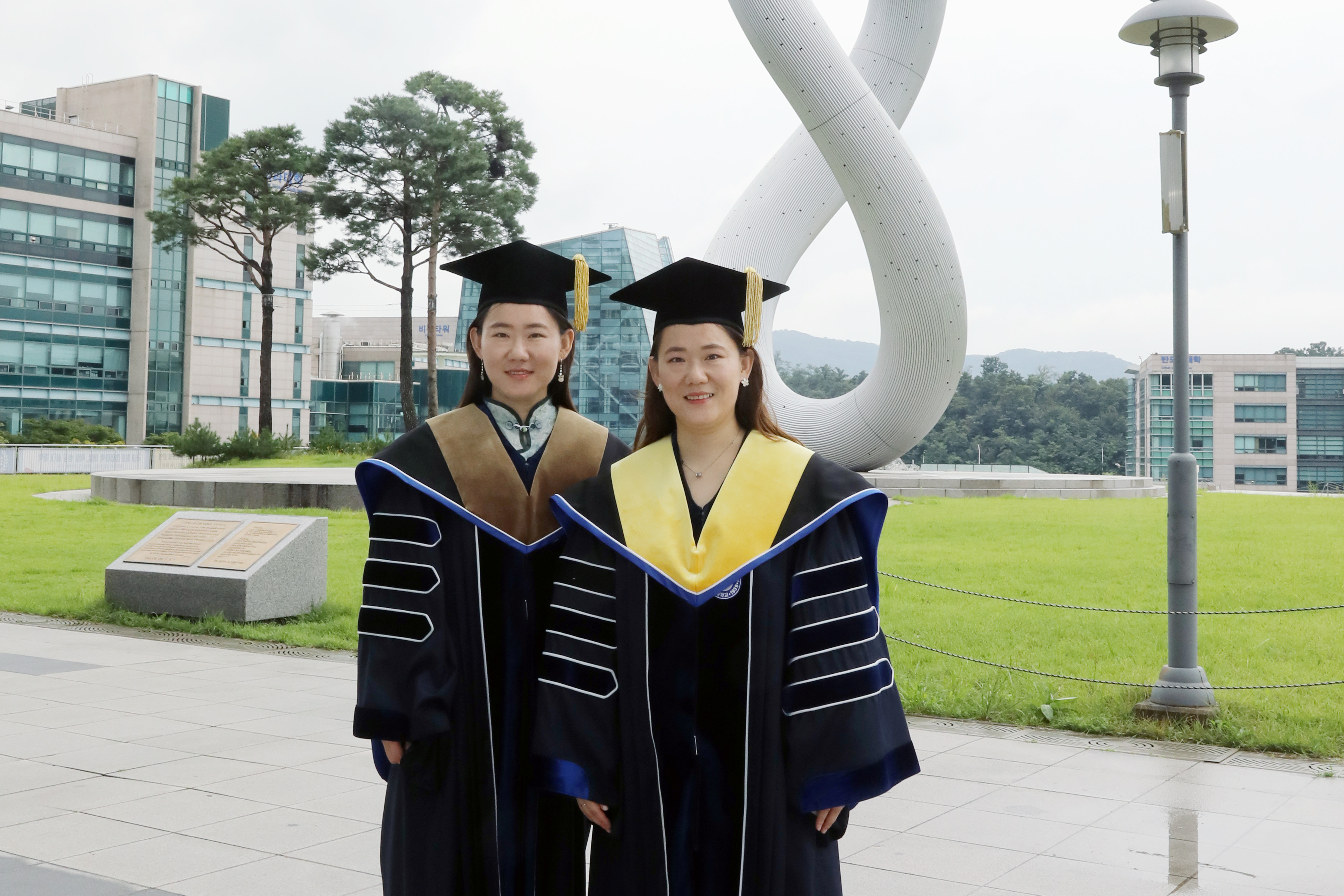 오는 24일 가천대에서 나란히 박사학위를 받는 중국인 쌍둥이 유학생인 언니 유하이징(왼쪽)과 동생 유하이닝(오른쪽)이 대학 가천관 잔디광장에서 학위복을 입고 기념사진을 촬영하고 있다. 가천대 제공