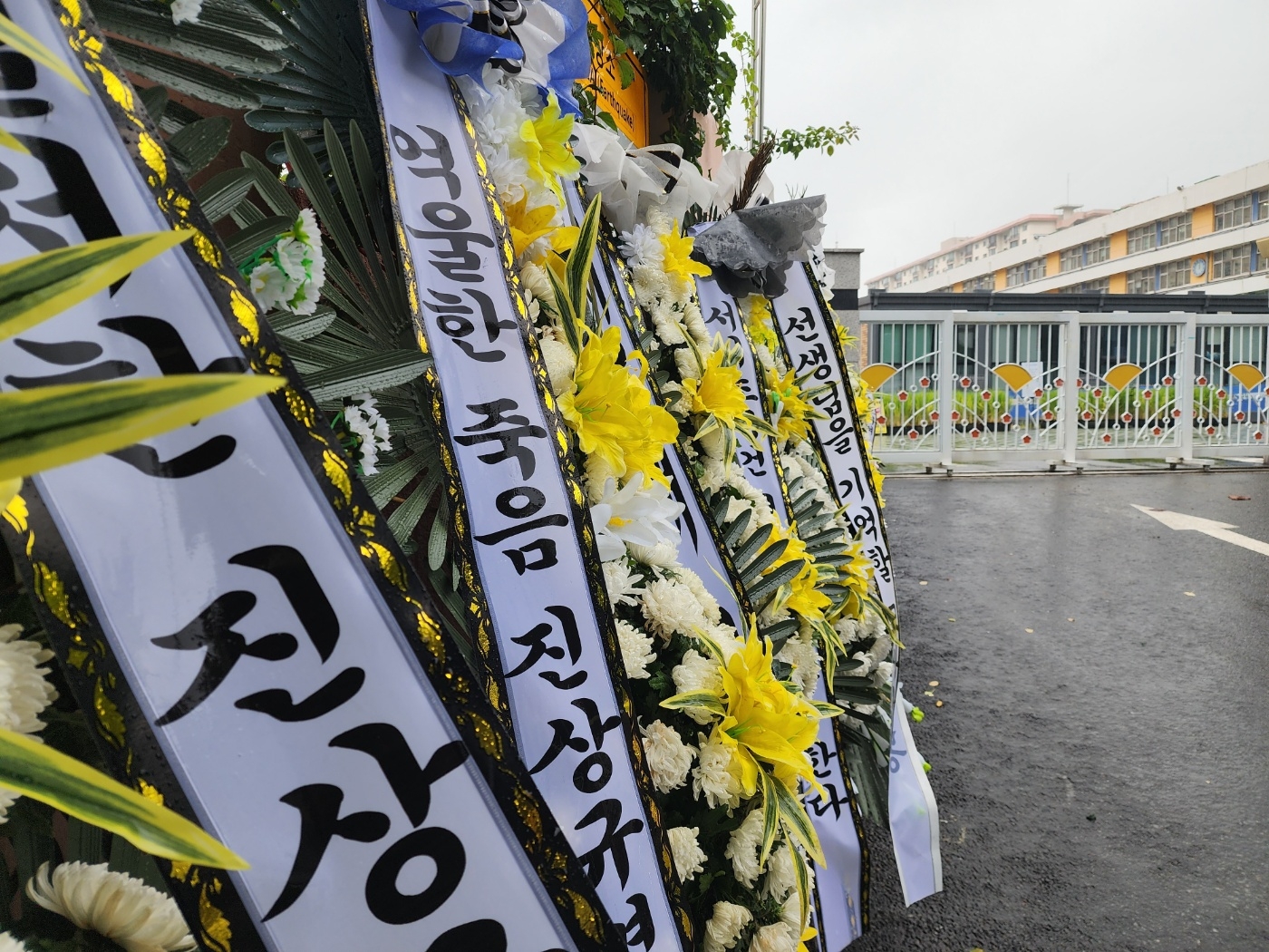 23일 서울 서초구 서이초등학교 정문 앞 조화에 진상규명을 요구하는 글이 적혀 있다. 김중래 기자