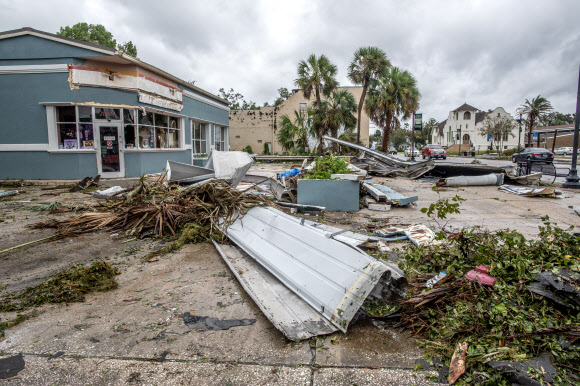 허리케인 이달리아가 미국 플로리다주에 상륙한 30일(현지시간) 페리 마을의 주택이 강풍에 심각하게 훼손돼 잔해들이 어지럽게 나딩구는데 자동차들이 지나가고 있다. 페리 마을 EPA 연합뉴스