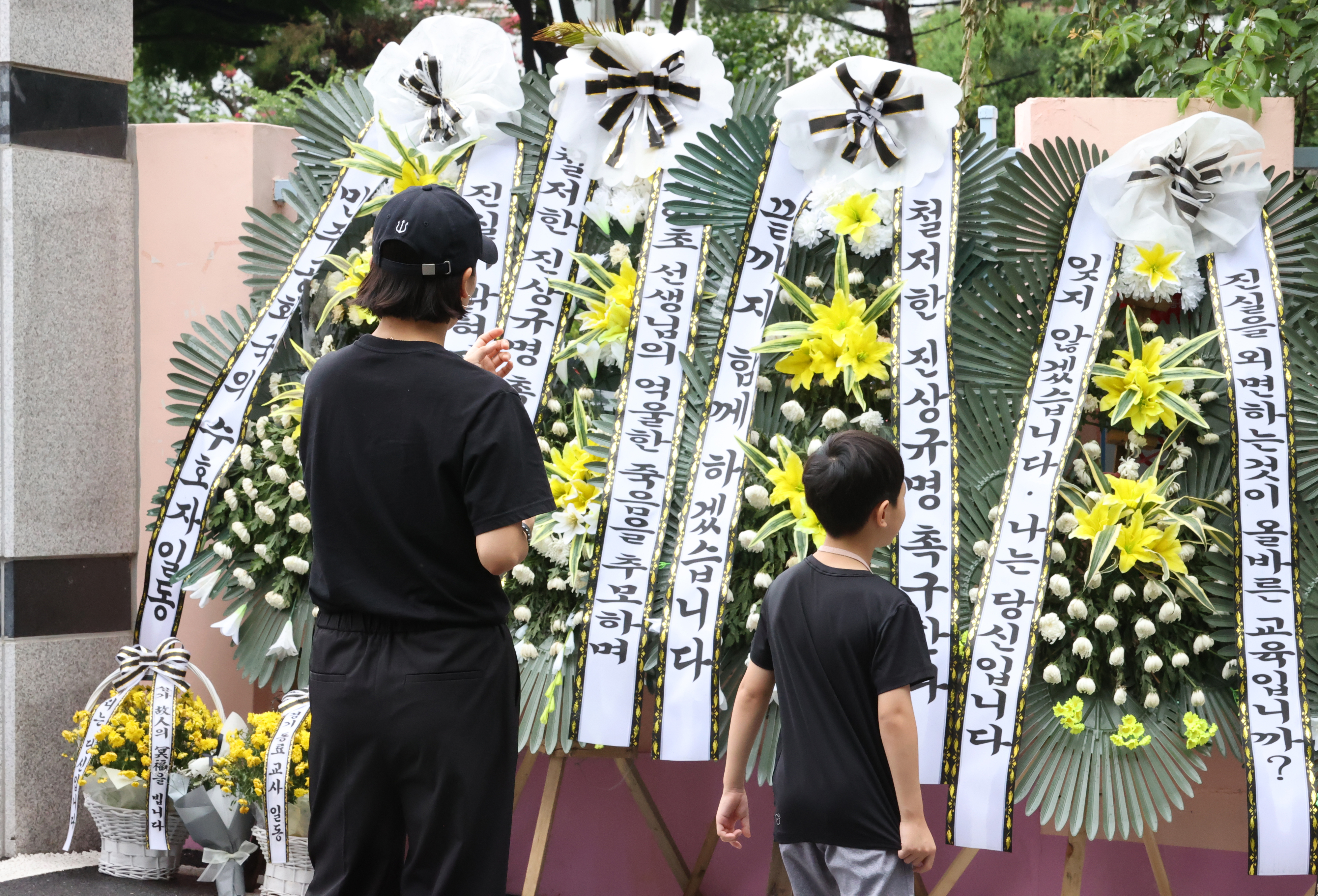 재량휴업일을 하루 앞둔 3일 서울 서초구 서이초등학교에서 추모객들이 조화를 바라보고 있다. 전국 교사들은 극단적 선택을 한 서이초 교사의 49재인 4일을 ‘공교육 멈춤의 날’로 선언하고 방과 후 추모 집회를 연다. 연합뉴스