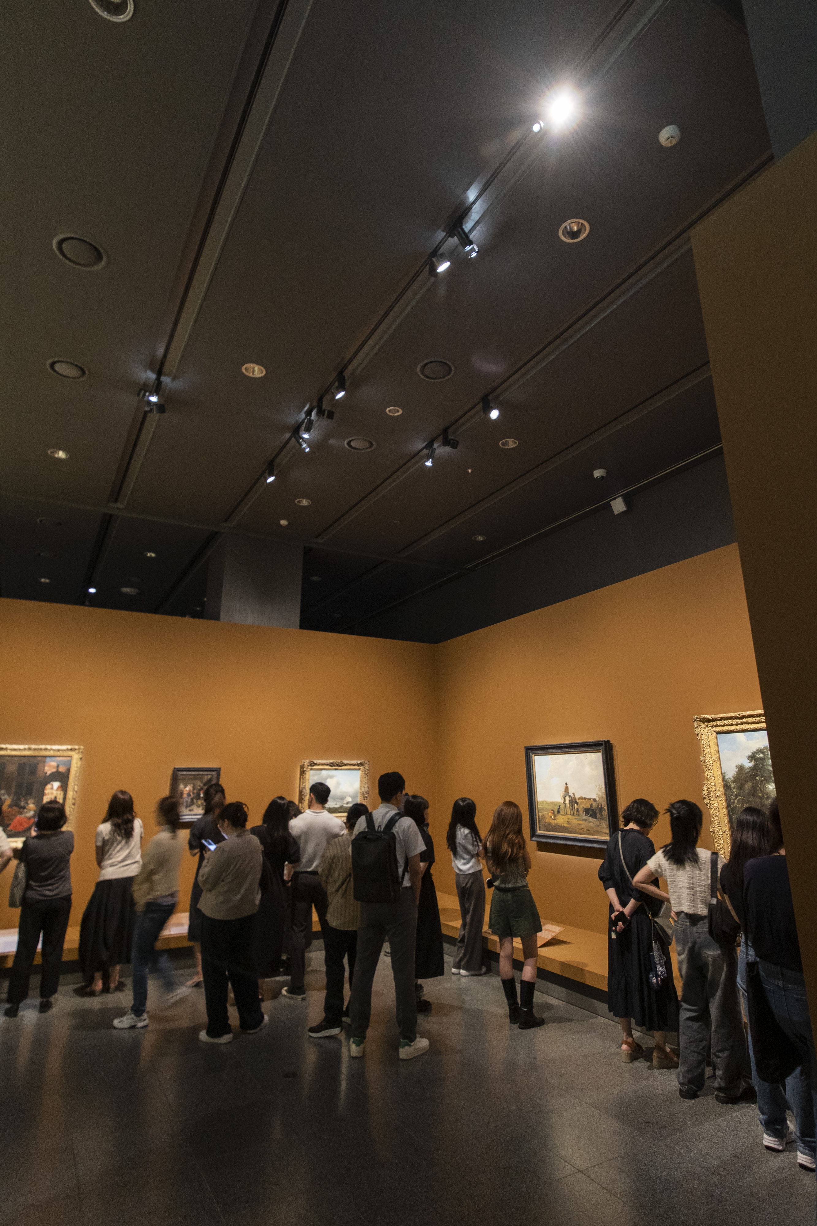 국립중앙박물관 ‘거장의 시선 사람을 향하다’에서 천장에 달린 조명을 받은 그림들을 관람객들이 보는 모습.