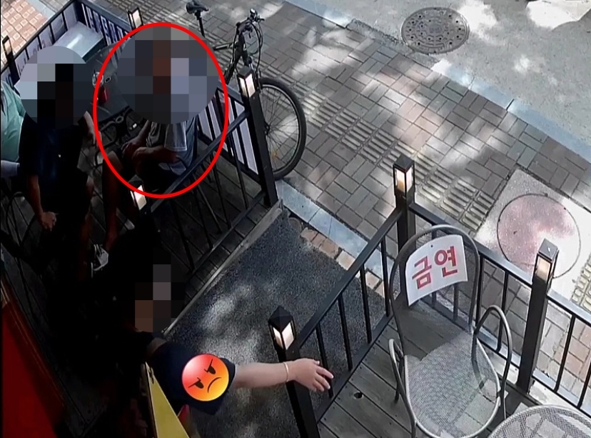 ‘금연’이라는 문구가 쓰여 있는 카페테라스에서 한 남성(붉은 원)이 커피를 마시며 담배를 피우자 해당 카페 사장이 ‘금연’ 문구를 가리키며 흡연을 자제해달라고 부탁하는 모습. 온라인 커뮤니티