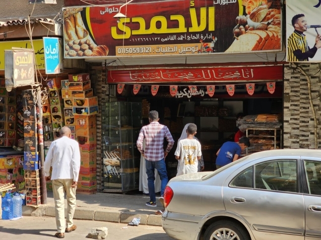 8일(현지시간) 이집트 카이로와 기자주의 경계에 위치한 도끼의 모한디신 거리에서 수단 이주민들이 빵을 사기 위해 가게로 들어가고 있다. 연합뉴스