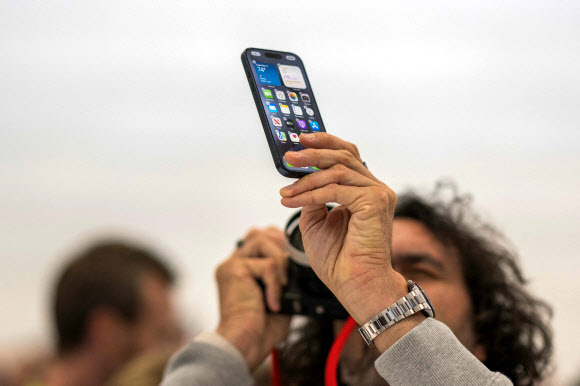 미국 캘리포니아주 쿠퍼티노의 애플파크에서 12일(현지시간)  아이폰15시리즈 신제품 공개 행사가 열렸는데 한 참가자가 아이폰15 프로 제품을 카메라에 담고 있다. 쿠퍼티노 AFP 연합뉴스