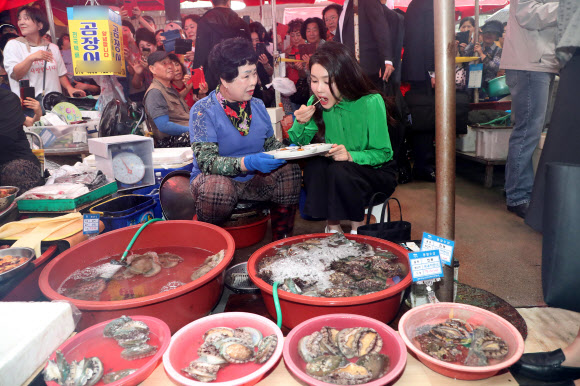 윤석열 대통령 부인 김건희 여사가 14일 부산 기장시장을 찾아 전복을 맛보고 있다.   2023.9.14 연합뉴스