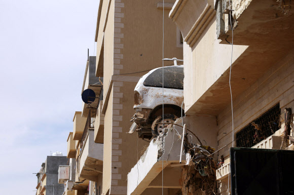 리비아에 대홍수 재앙이 덮친 지 일주일이 지난 17일(현지시간) 데르나 시의 주거용 건물 위층에 떠밀려와 처박힌 자동차가 그대로 방치돼 있다. 데르나 로이터 연합뉴스