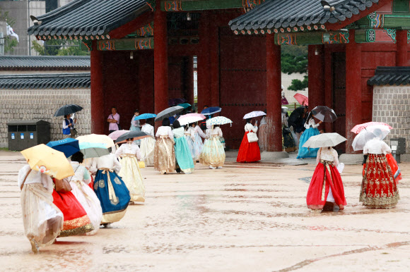20일 서울 종로구 경복궁에서 한복을 입은 관광객들이 비를 피해 발걸음을 재촉하고 있다. 2023.9.20 연합뉴스