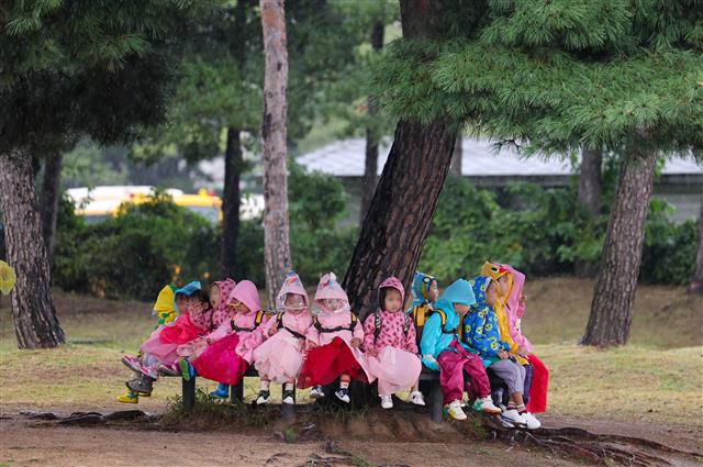 가을비가 내리는 20일 서울 종로구 경복궁을 찾은 유치원생들이 비를 피해 나무 밑에서 휴식을 취하고 있다. 2023.9.20. 뉴스1